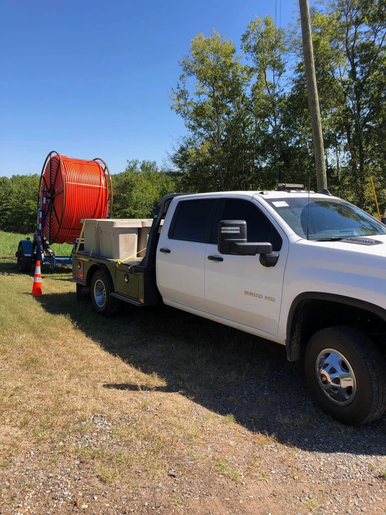 Chevrolet 3500 HD truck towing a large spool of orange conduit